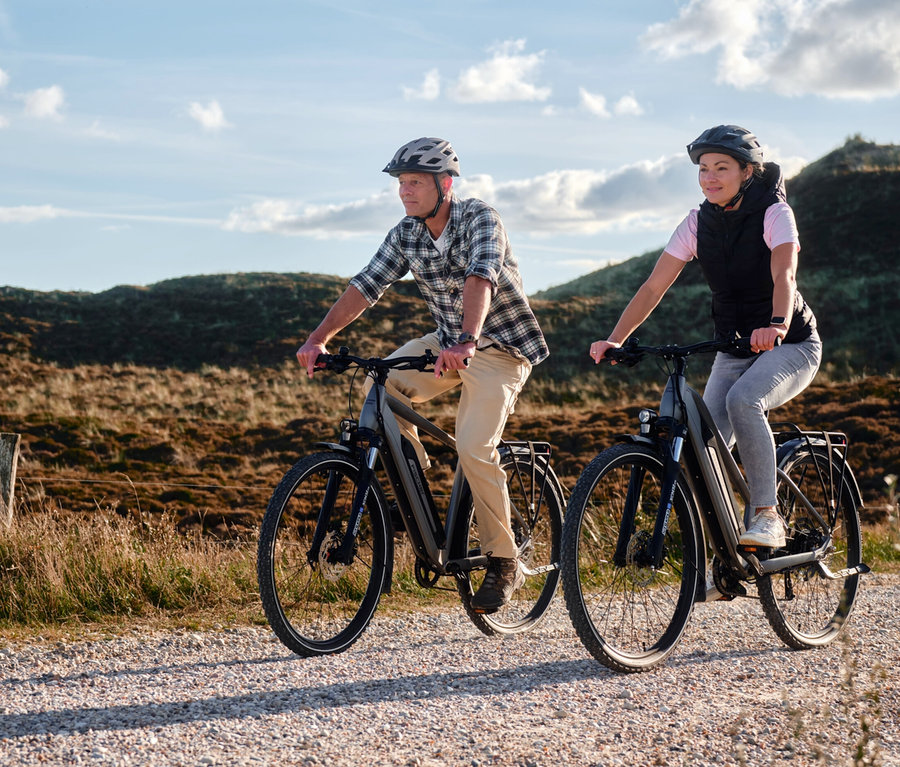 Ein Mann und eine Frau fahren auf Schotterwegen mit FISCHER Trekking-E-Bikes TERRA 2.2 ACTIVE mit Trapezrahmen.
