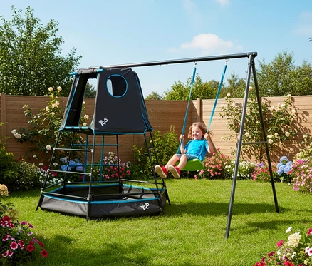Ein Kind schwingt auf dem Kletterturm »Explorer« mit Schaukel im Garten.