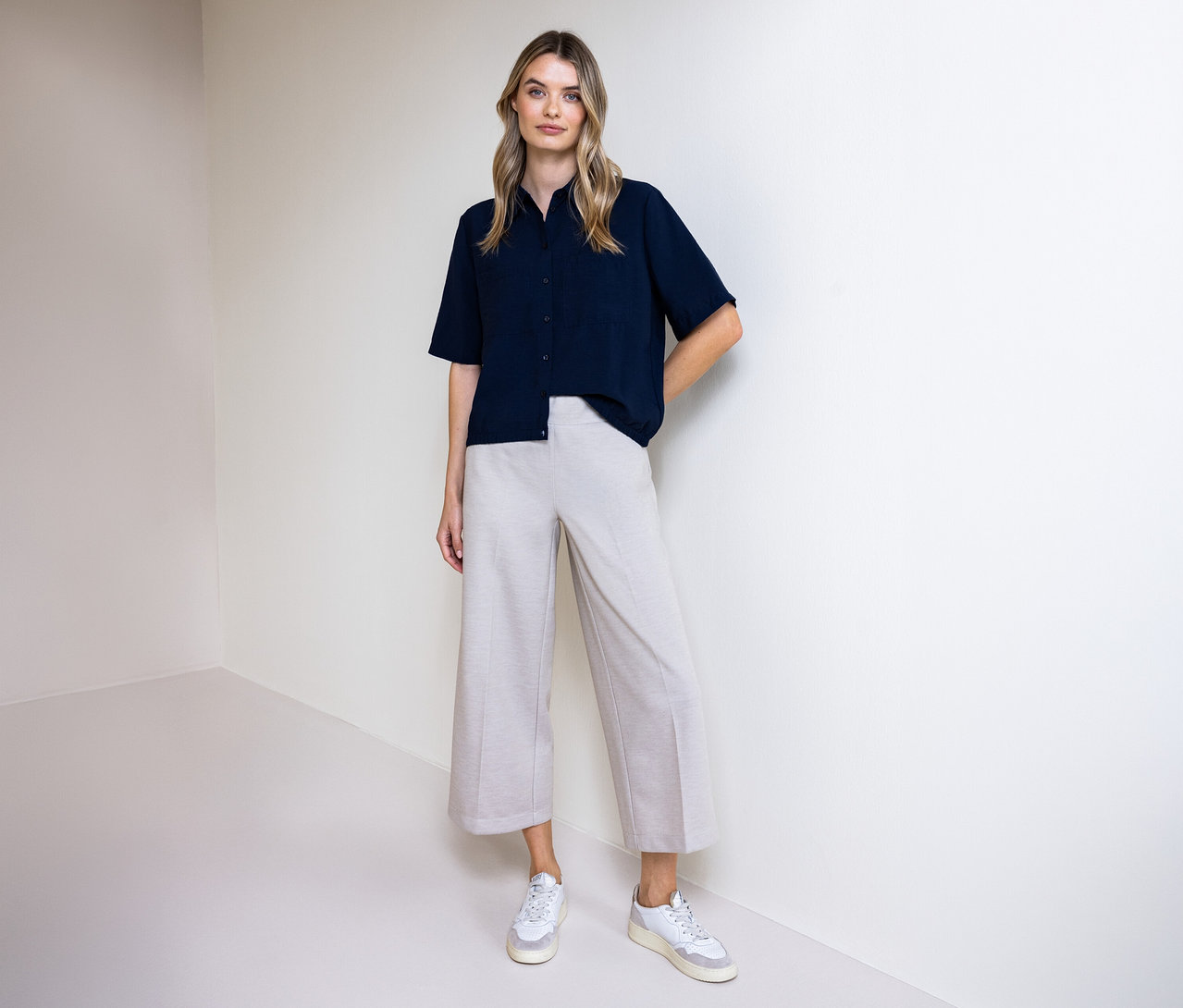 Frau in Hose und Street One Hemdbluse. Sie steht vor einer Wand.