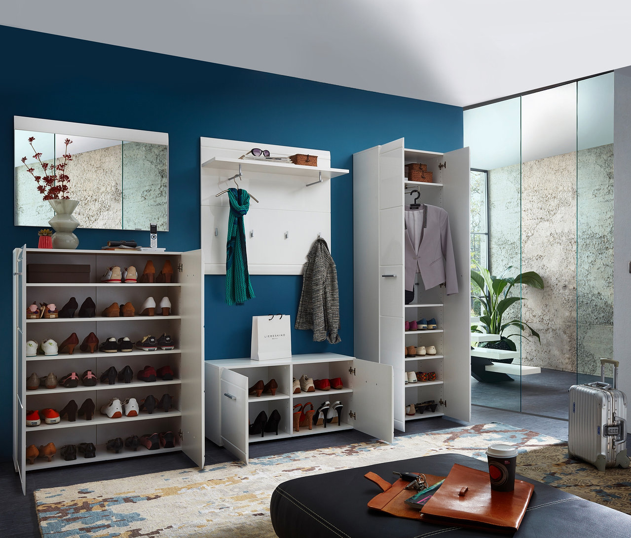 Eingangsbereich mit weißer Schuhbank »ADANA«, Schuhregalen und Garderobe vor blauer Wand.