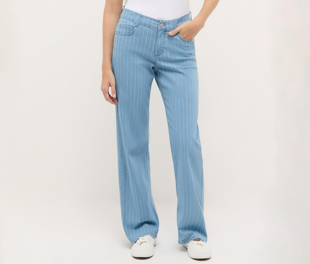 Frau trägt eine blaue Angels Denim »Liz« Wide Leg Jeans mit Streifen und weiße Turnschuhe.