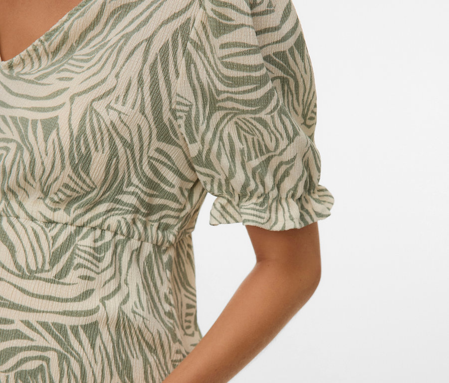 Nahaufnahme einer Frau, die ein Kleid mit grünem Zebramuster trägt.