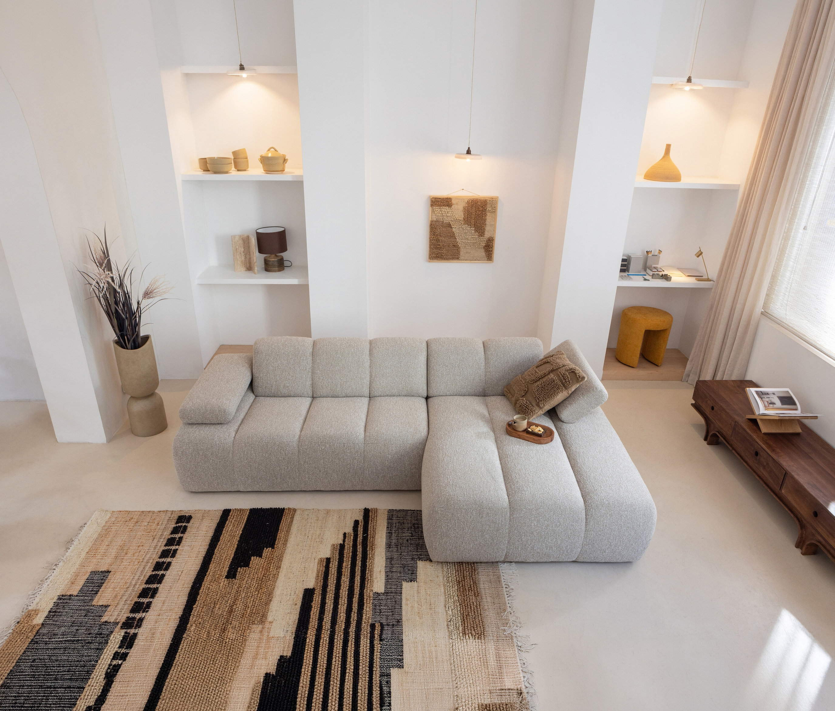 Wohnzimmer mit beigem Sofa, Kissen und Woood Teppich »Liberal«, 170 x 240 cm. Regale und Deko an der Wand.