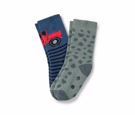 Zwei Kindersocken: eine blaue Socke mit rotem Lastwagen und schwarz-blauen Streifen, die andere grün mit dunkelgrünen Flecken.
