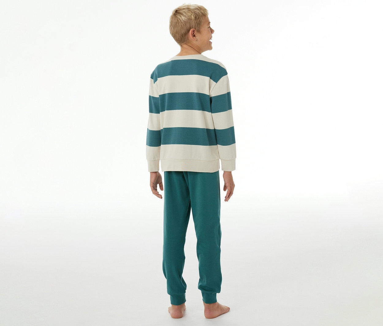 Junge von hinten, trägt einen SCHIESSER Kinder-Interlock-Pyjama mit teal-creme gestreiftem Oberteil und tealfarbener Hose.