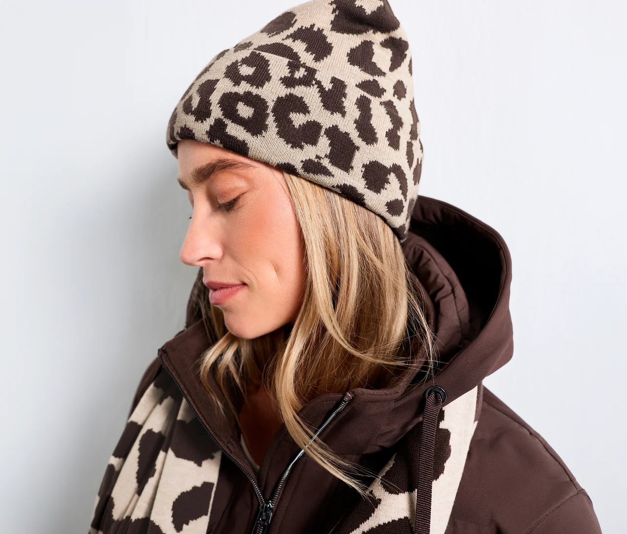 Frau trägt eine Street One Strickmütze mit braunem Leopardenmuster, eine braune Jacke und einen passenden Schal.