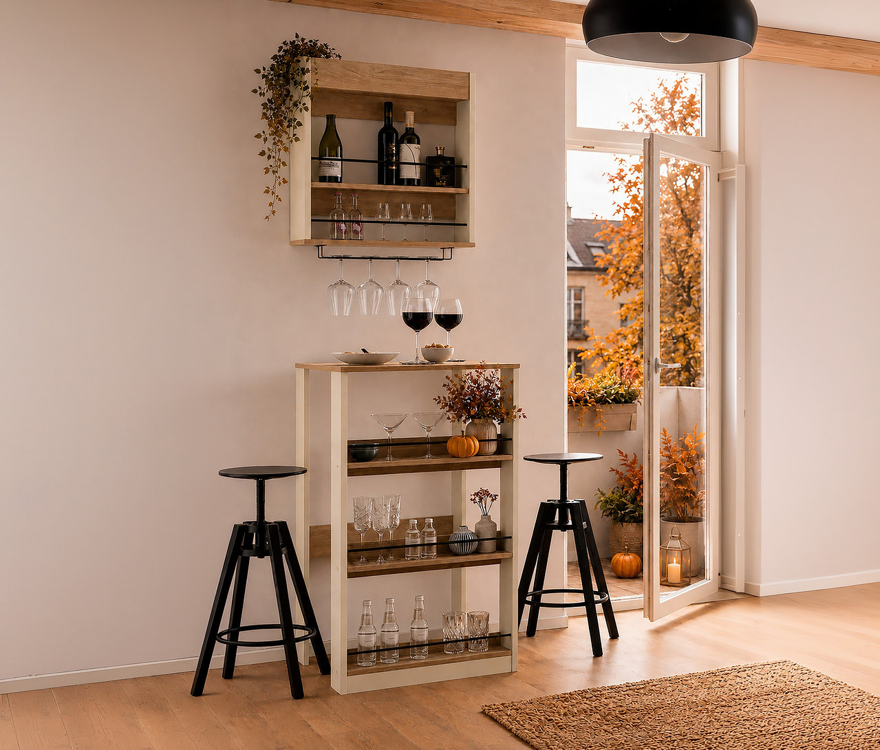 Ein cremebeiges Barregal „Kolari“ hängt über einem cremebeigen Stehtisch „Kolari“ mit Gläsern und Herbstdeko. Zwei schwarze Barhocker stehen davor, daneben ein offener Balkon mit Herbstbäumen.
