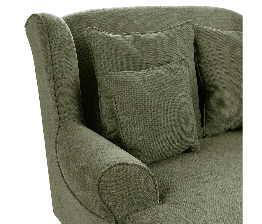 Nahaufnahme eines grünen Polstersessels oder Sofas mit geschwungener Arm- und Rückenlehne, darauf zwei quadratische Kissen aus olivgrünem Strukturstoff.