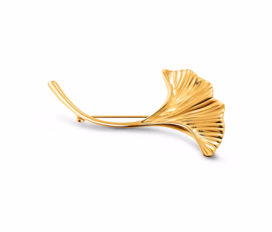 Eine goldene Brosche »Ginkgoblatt« liegt auf einem weißen Hintergrund.