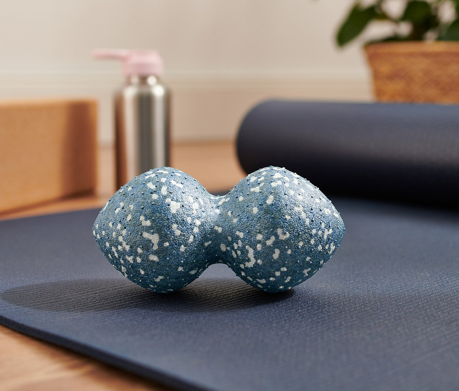 Ein blauer Duo-Massageball liegt auf einer blauen Yogamatte.
