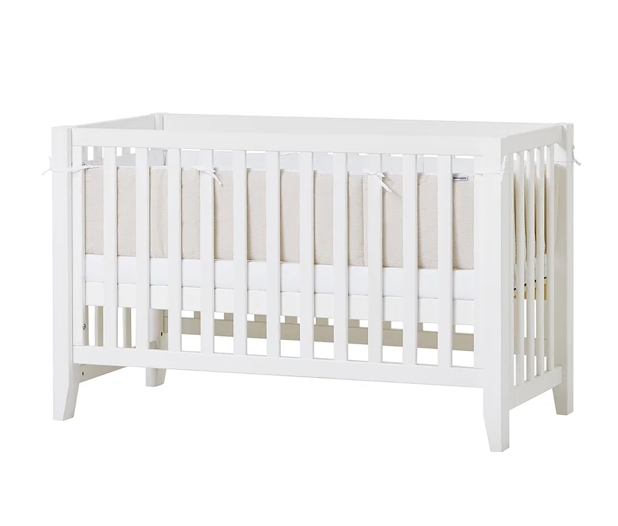 Ein weißes Hoppekids Babybett "Anton" mit beiger Einlage.