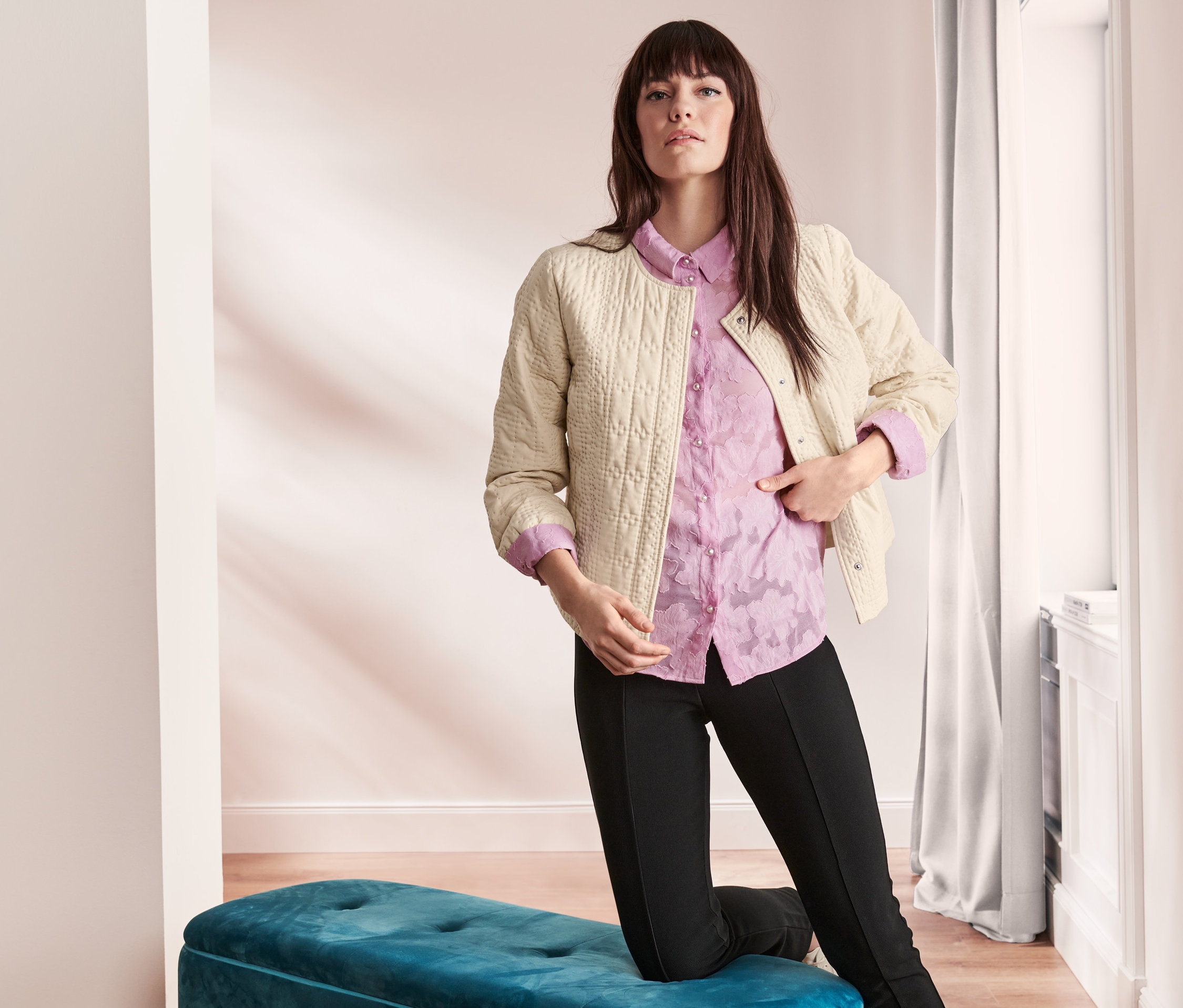 Frau posiert in leichter Jacke und lila Hemd.
