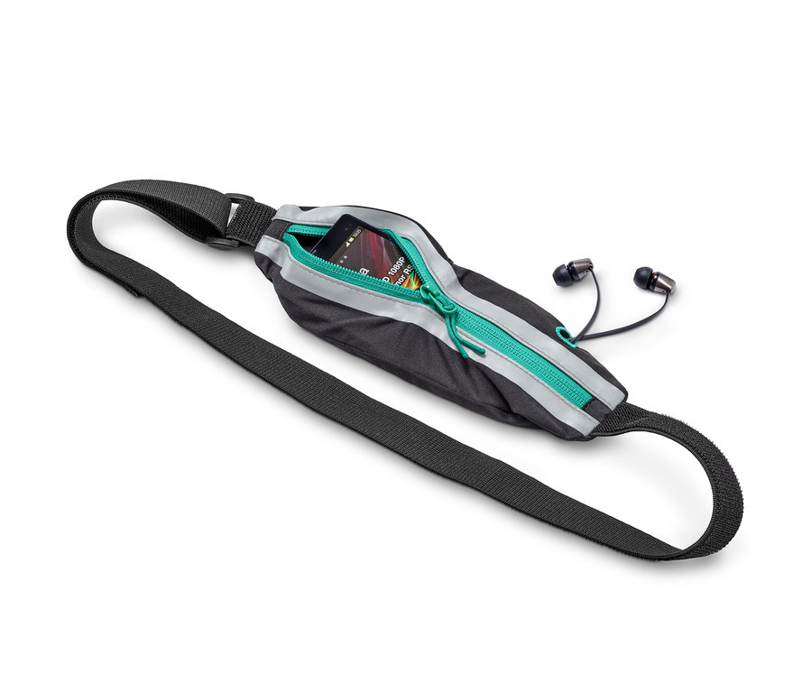 Ein schwarzer Sportgürtel mit einem Telefon drinnen und Kopfhörern daneben.