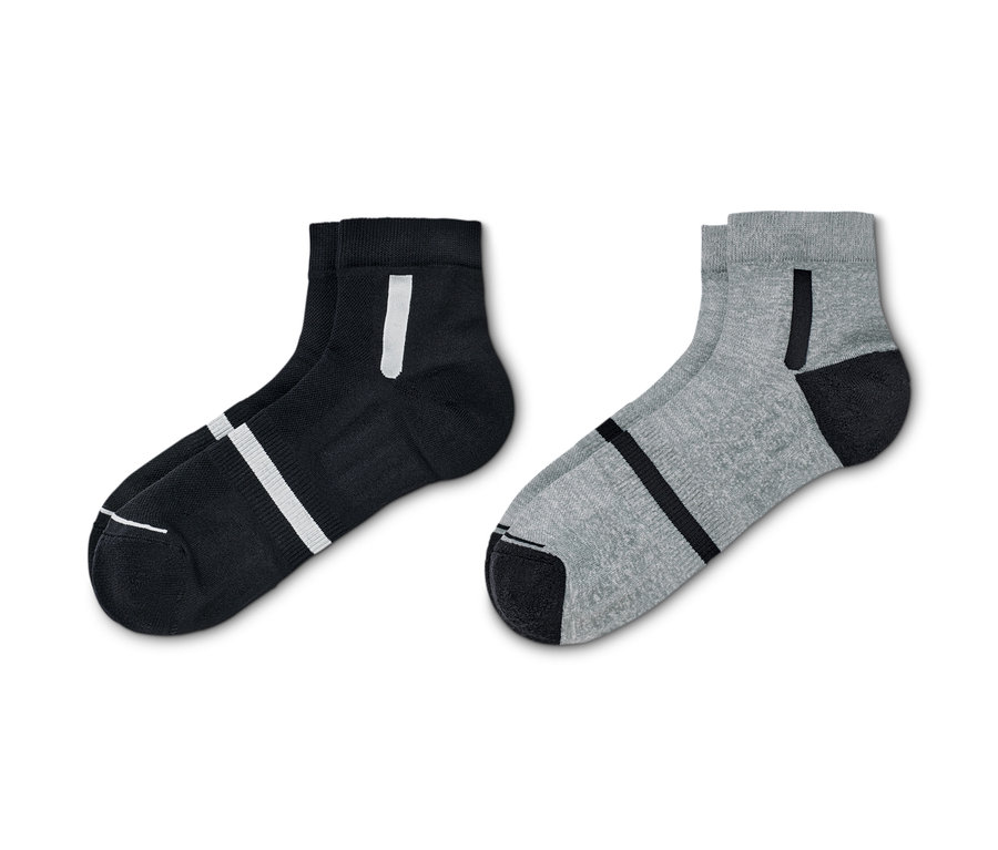 Zwei Paar Sportsocken. Ein Paar ist schwarz mit weißen Streifen, das andere grau mit schwarzen Streifen.