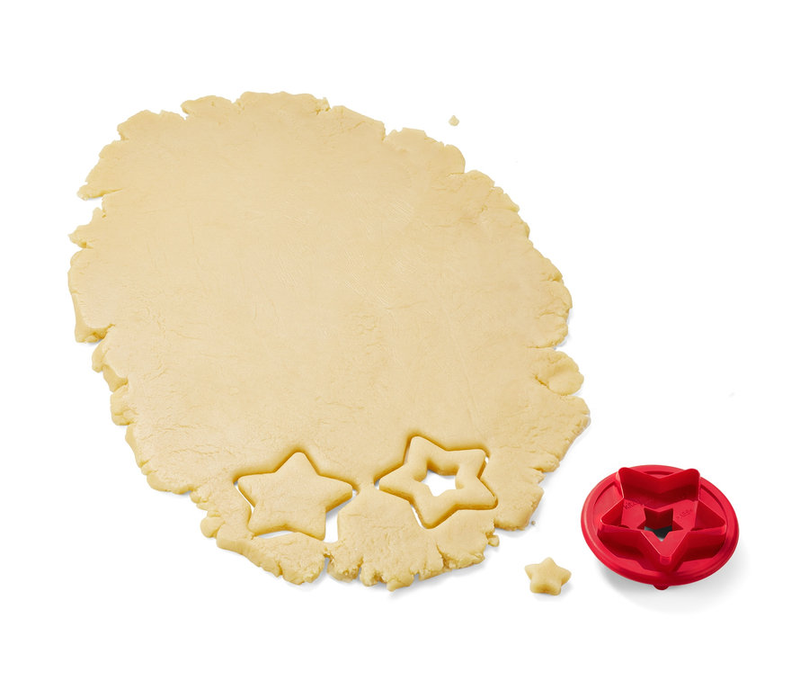 Ausgerollter Teig mit zwei ausgestochenen Sternen und einem roten 3 Linzer-Plätzchen-Ausstecher.