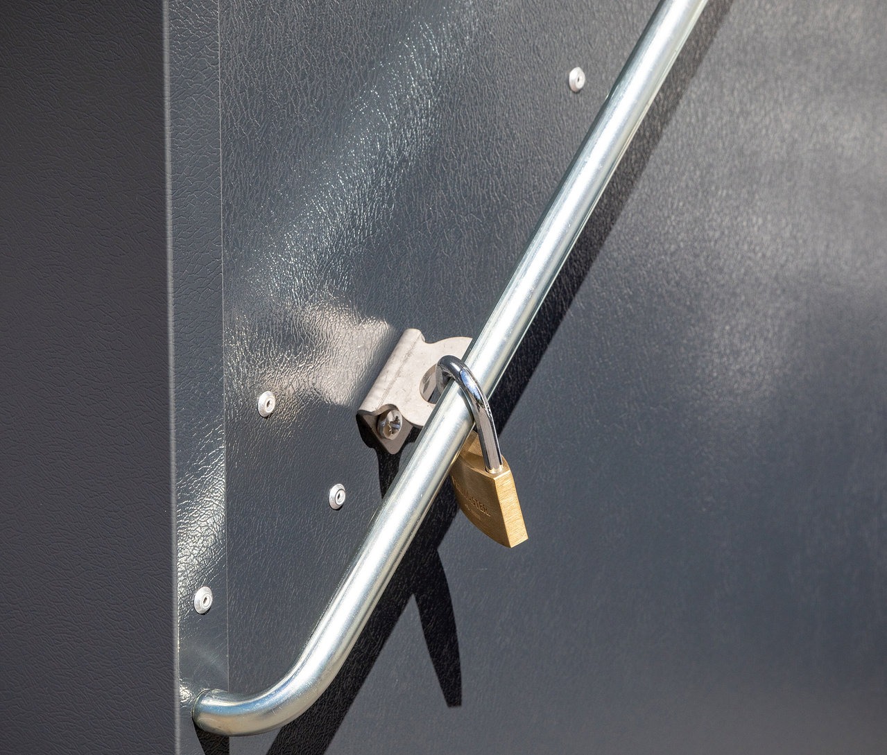 Detailansicht einer grauen Gerätebox »Storeguard« mit Vorhängeschloss an einem silbernen Griff.