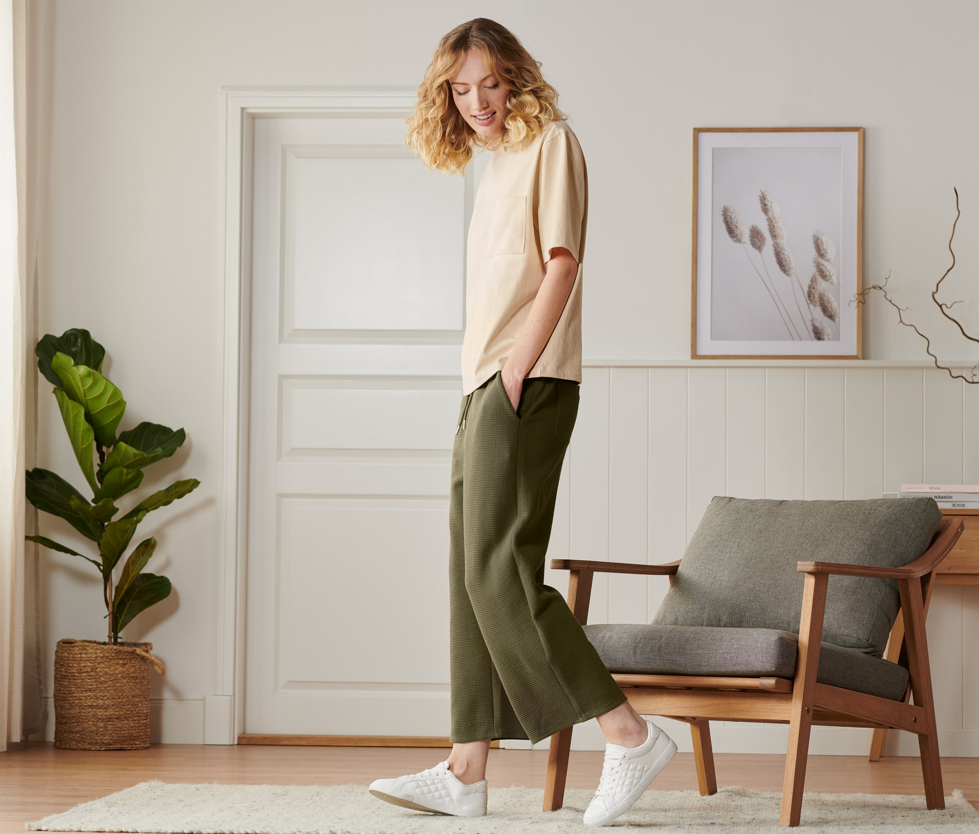 Eine Frau geht in einer khaki Sweat-Culotte und weißen Schuhen.