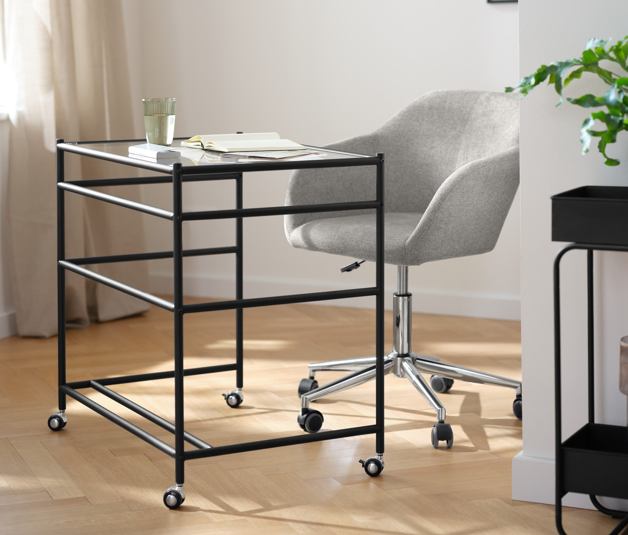 Ein Glasschreibtisch »CN3« mit Rollen und ein beiger Schreibtischstuhl stehen in einem Raum.