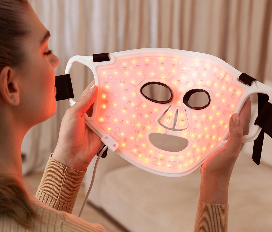 Frau hält eine leuchtende Silk'n LED-Gesichtsmaske 100.