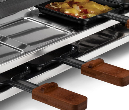 Detailaufnahme eines Raclettes für 8 Personen mit Pfännchen und Essen.