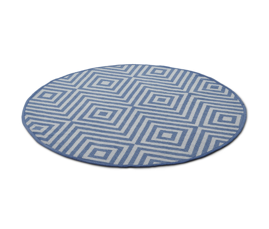 Ein runder blauer Outdoor-Wendeteppich mit geometrischem Muster.