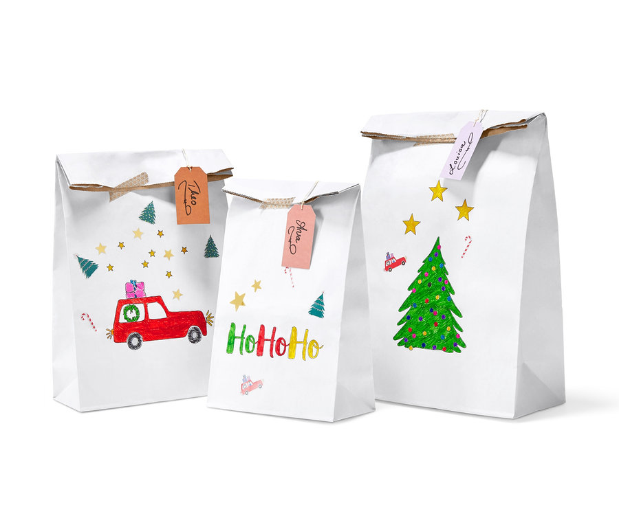 Drei weiße Papiertüten mit weihnachtlichen Zeichnungen und Namensschildern. Papiertüten-Bastel-Set.