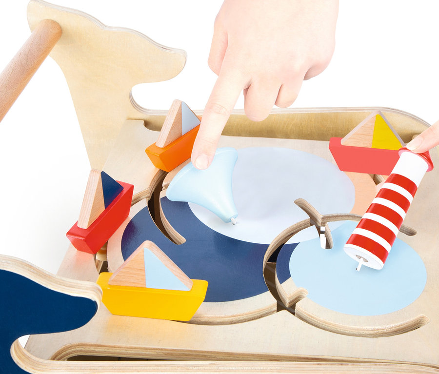 Kinderhände spielen mit dem hölzernen small foot Activity Lauflernwagen »Wal« mit Wal-, Boots- und Leuchtturmmotiven.