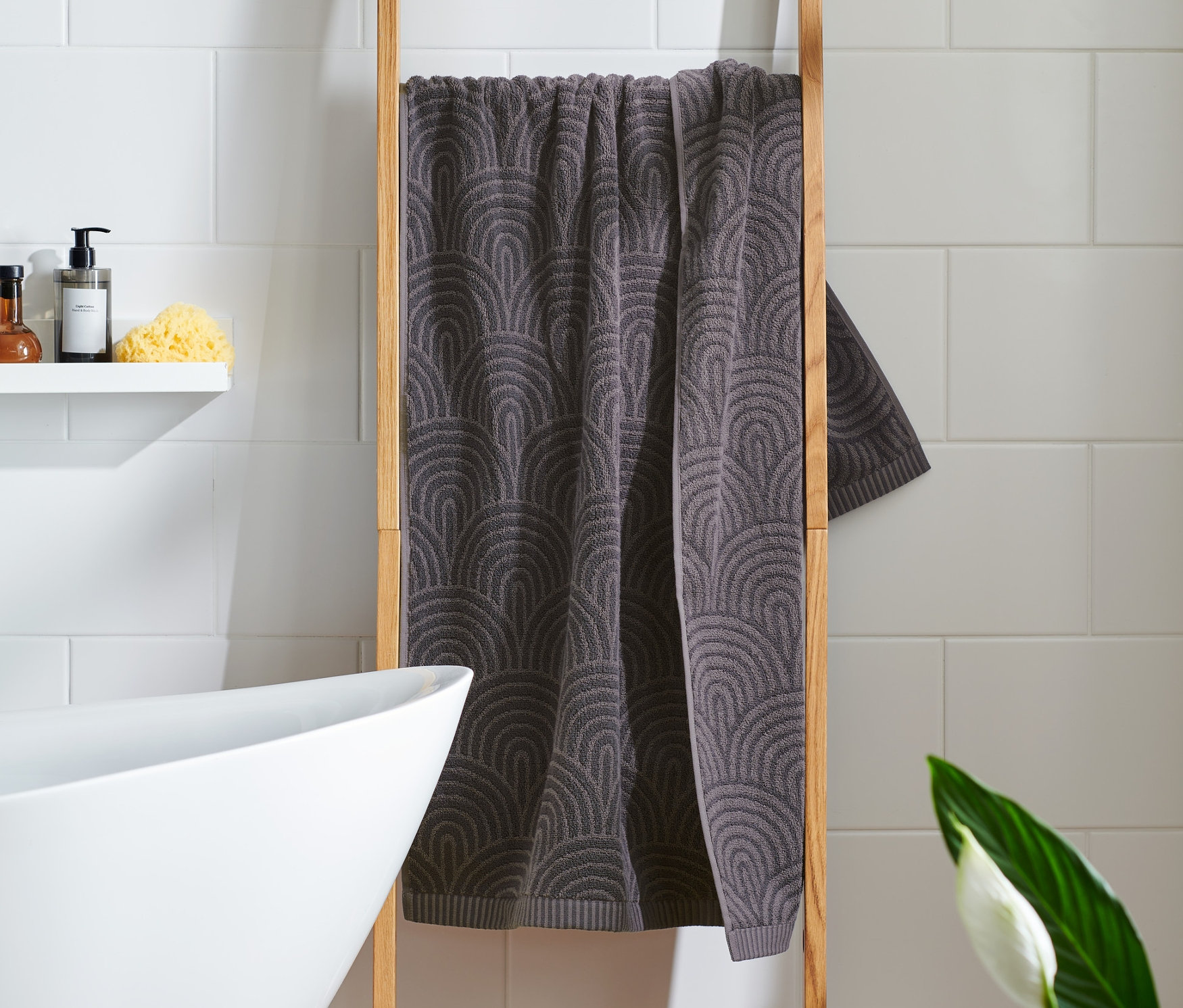 Ein anthrazitfarbenes Premium-Badetuch hängt an einer Holzleiter.