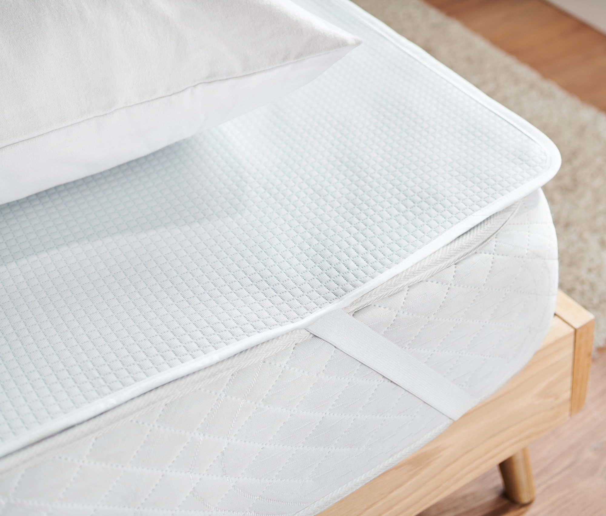 Auf einer Matratze liegen eine Matratzenspannauflage und ein weißes Kissen.