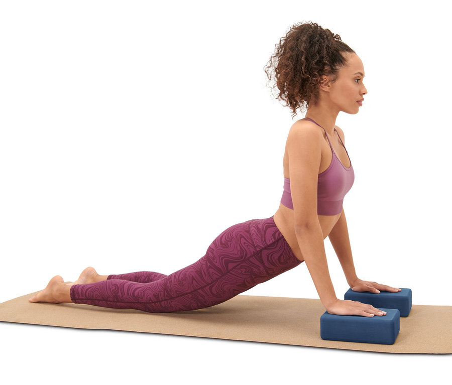 Frau macht Yoga auf einer Yoga-Matte mit zwei blauen Yoga-Blöcken aus dem Yoga-Set.