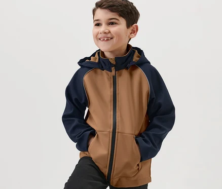 Junge lächelt und trägt eine Kinder-Softshelljacke.