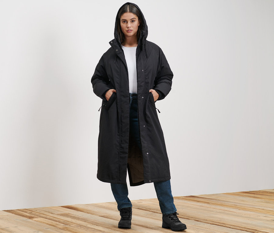 Frau steht und trägt einen extralangen Thermomantel und eine Slim-Denim »Fit Emma« in Dark Blue Denim.