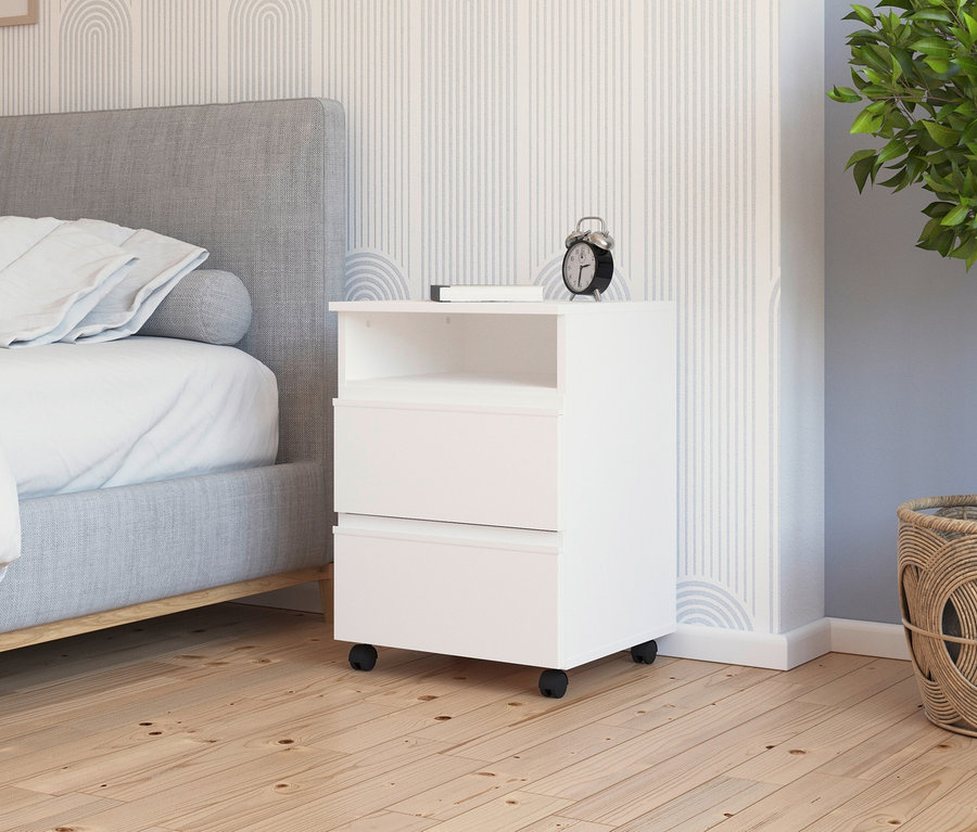 Detailaufnahme eines weißen rauch Rollnachttischs »Joel« neben einem Bett und einer Pflanze.