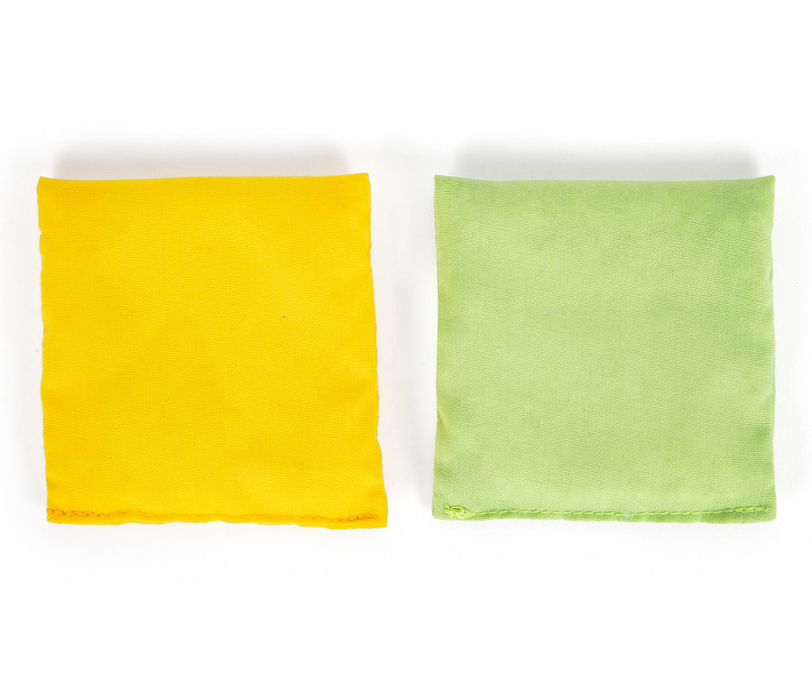 Zwei Stoffsäckchen, eines gelb und eines hellgrün, liegen nebeneinander auf einem weißen Hintergrund. Dargestellt sind die Säckchen des small foot Cornhole und Sling-Puck-Spiels.