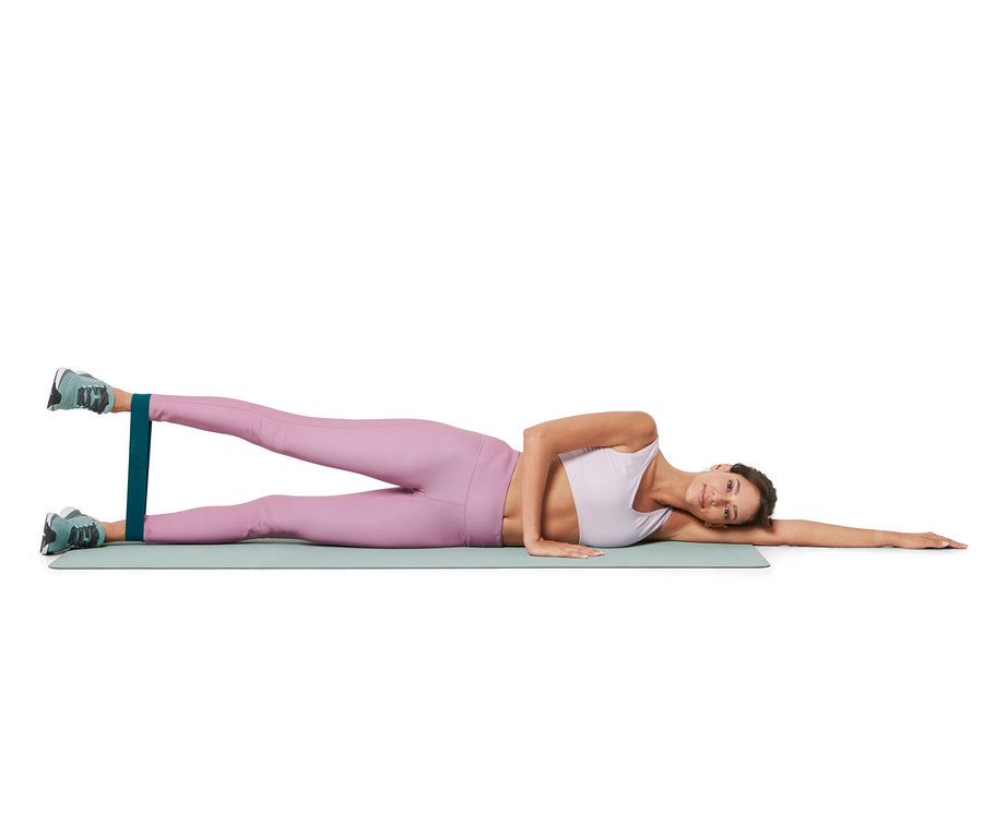 Eine Frau liegt seitlich auf einer Matte und trainiert mit 3 Trainingsbändern.
