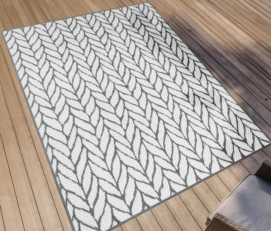 Grauer Outdoor-Wendeppich »Knitted Joy« mit Strickmuster liegt auf einer Holzterrasse.