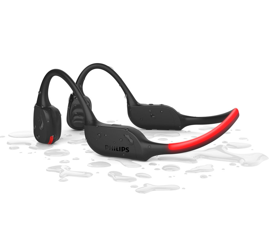 Zwei schwarze Philips Bone Conduction Sport-Kopfhörer liegen auf einem weißen Hintergrund mit Wassertropfen.