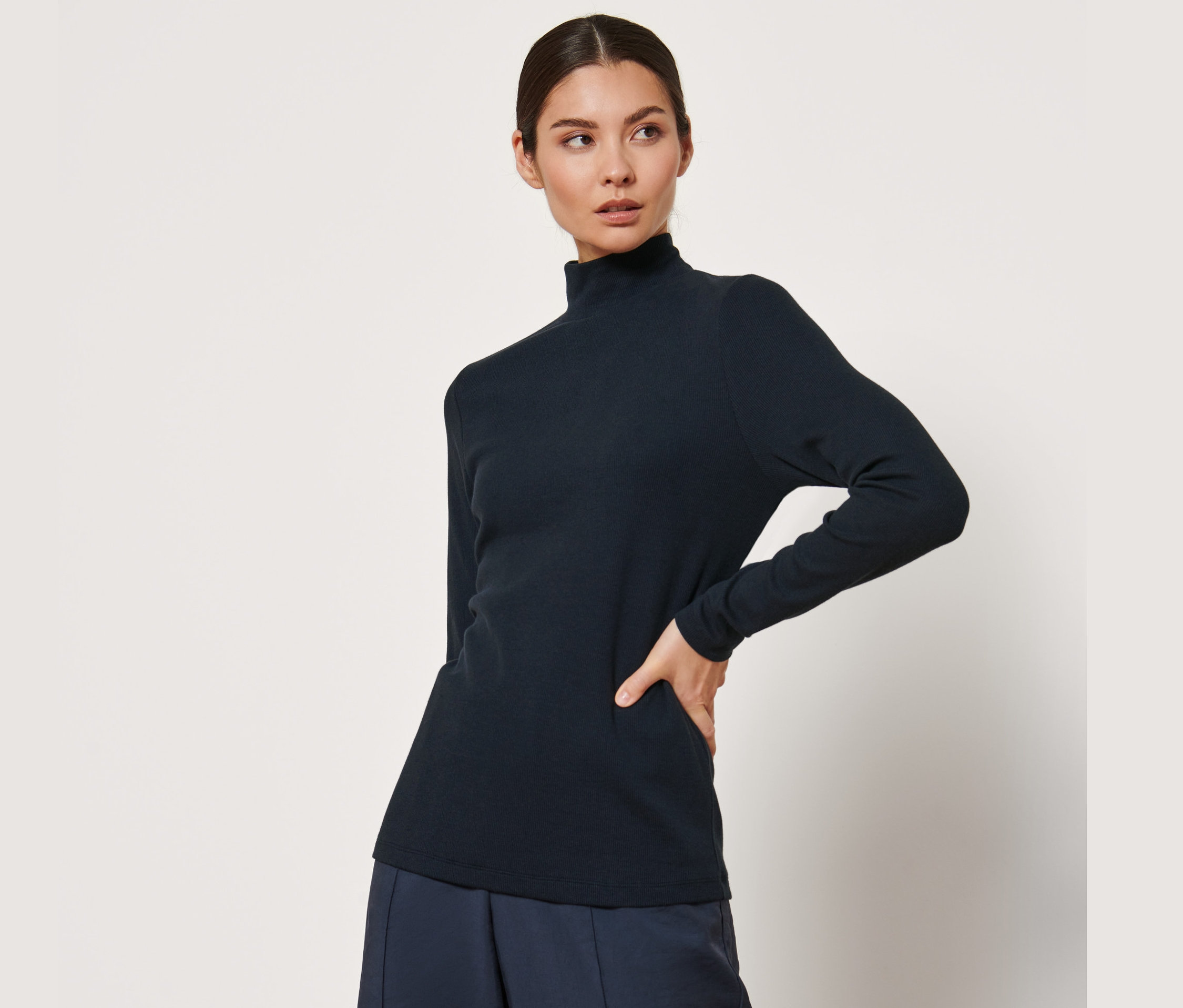 Frau posiert in einem schwarzen Langarmshirt.