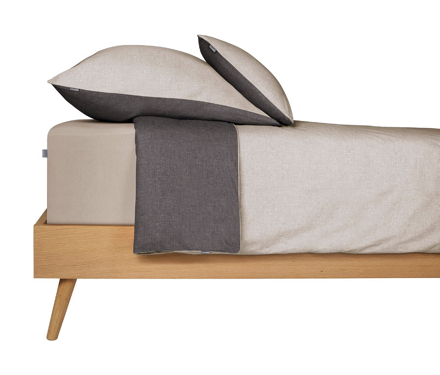 Hellbraune Bettwäsche und zwei Kissen auf einem Bett mit Holzrahmen.