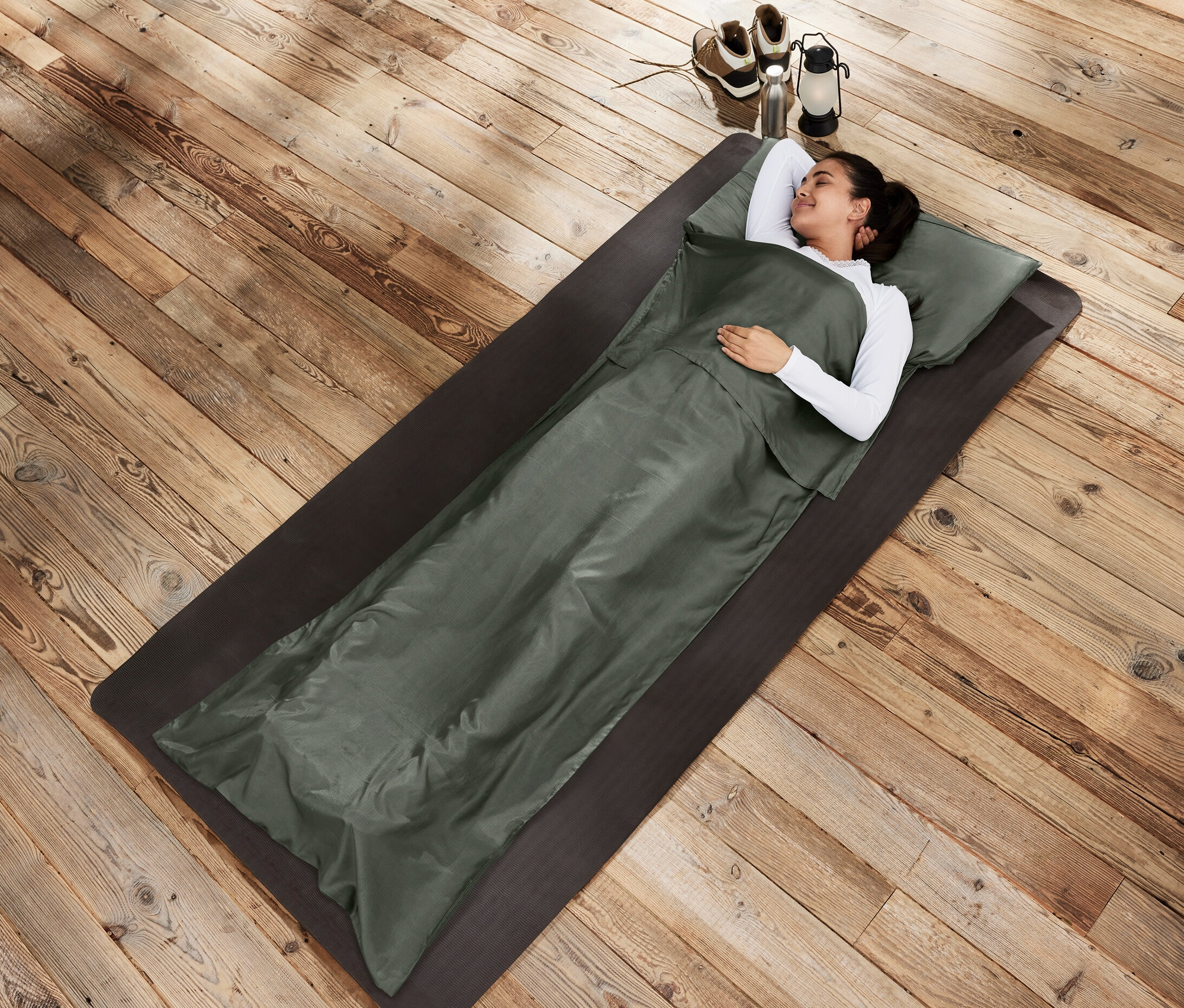 Frau liegt in Seiden-Schlafsack-Inlay auf einer Matte.