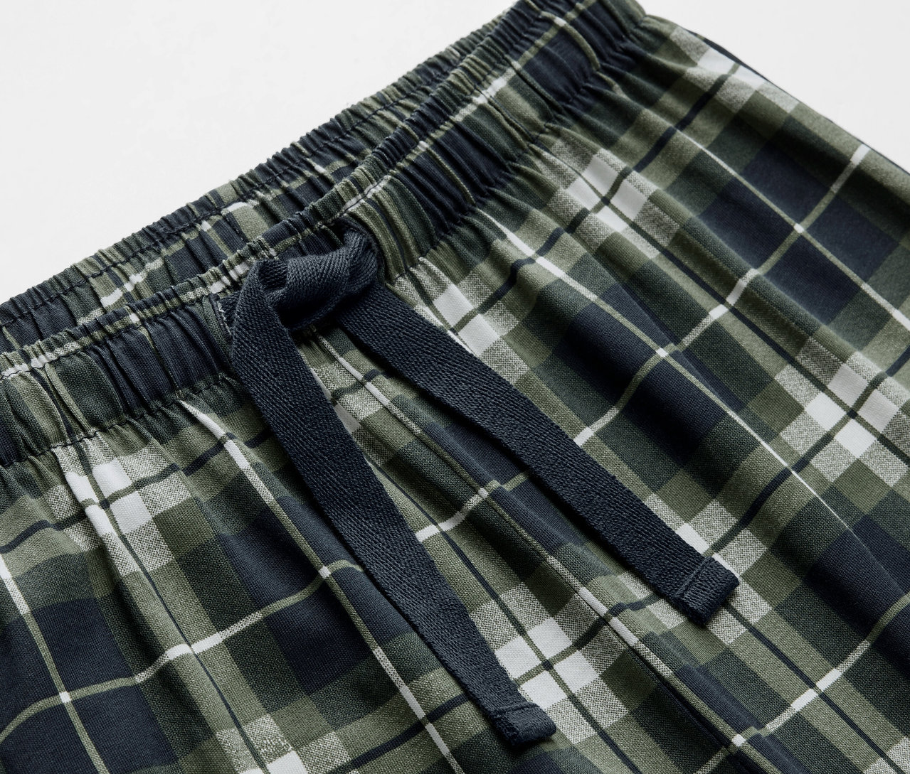 Detailaufnahme einer Kinderpyjamahose mit Karomuster und Kordelzug.