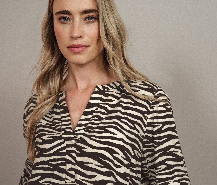 Porträt einer Frau mit blonden Haaren in einer Zebra-Bluse.