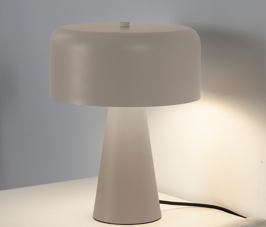Eine weiße Tischlampe steht auf einem weißen Tisch neben einem offenen Buch.