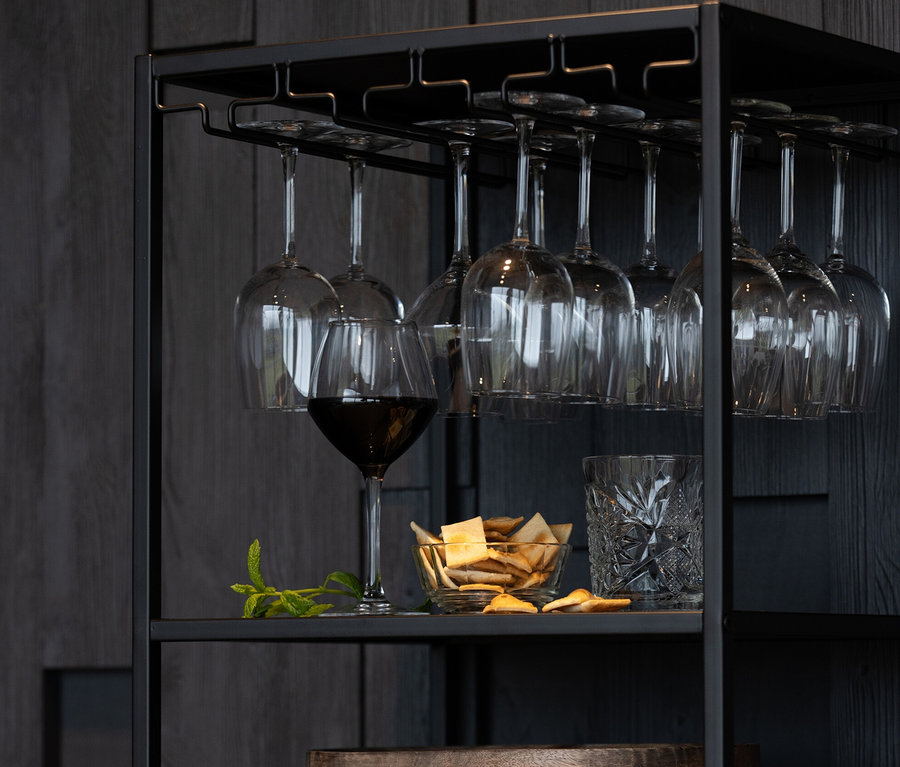 Schwarzes Metallregal »Reese« von Woood mit Weingläsern, Glas, Schale mit Crackern, Holzplatten und Weinflaschen.