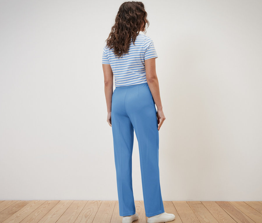 Frau von hinten trägt eine blaue Jerseyhose mit Biese und ein gestreiftes T-Shirt.