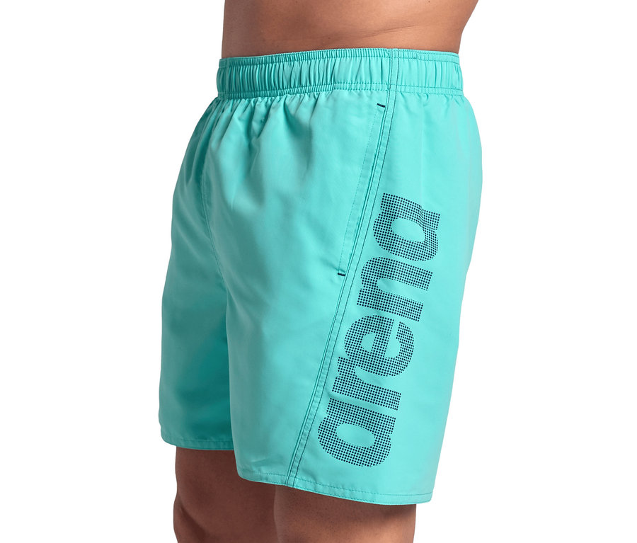 Mann posiert in hellblauen Arena Badeshorts Fundamentals Logo.