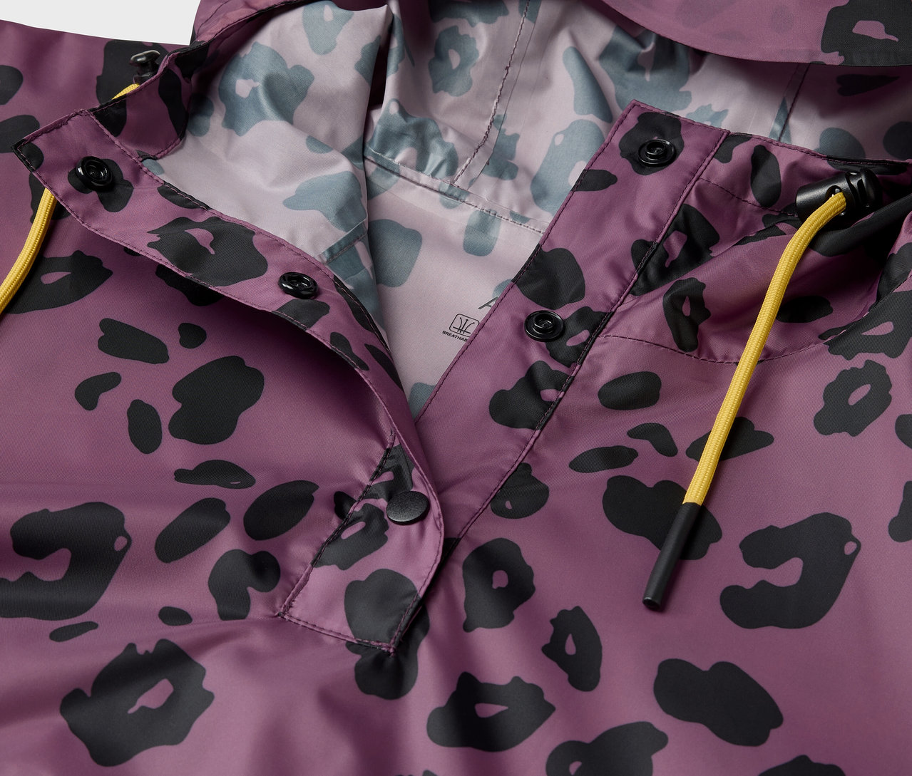 Detailaufnahme einer lila Jacke mit Kapuze und schwarzem Tiermuster.