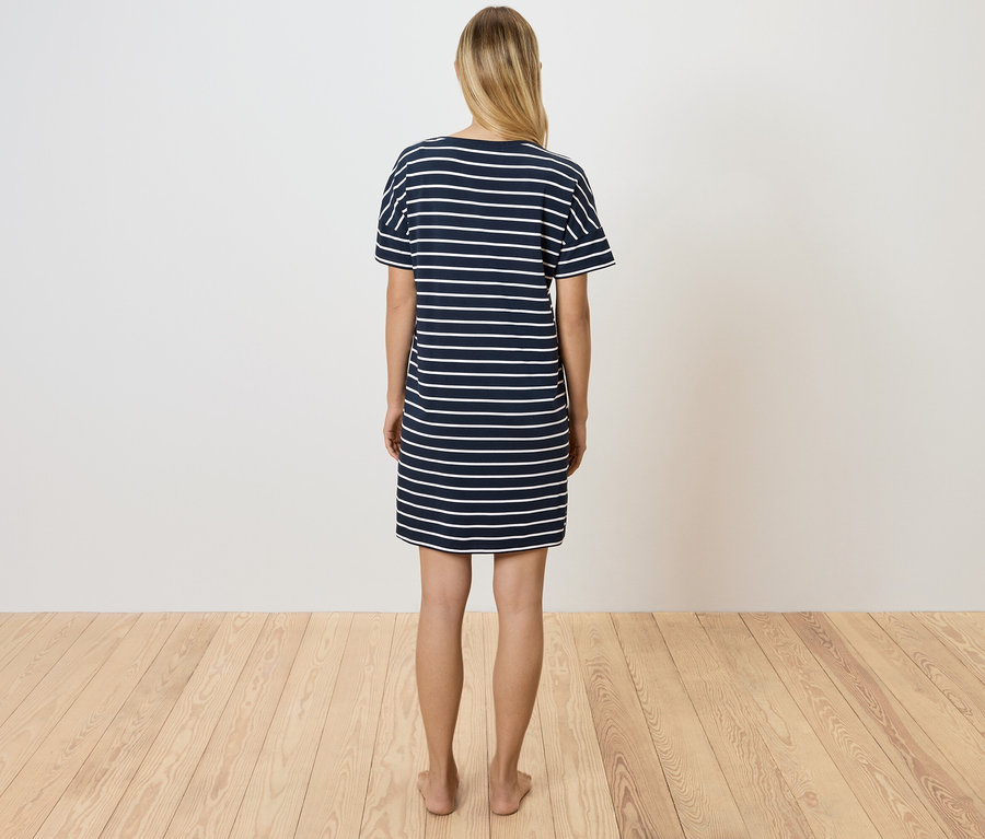 Frau steht mit dem Rücken zur Kamera und trägt ein blau-weiß gestreiftes T-Shirt-Kleid.