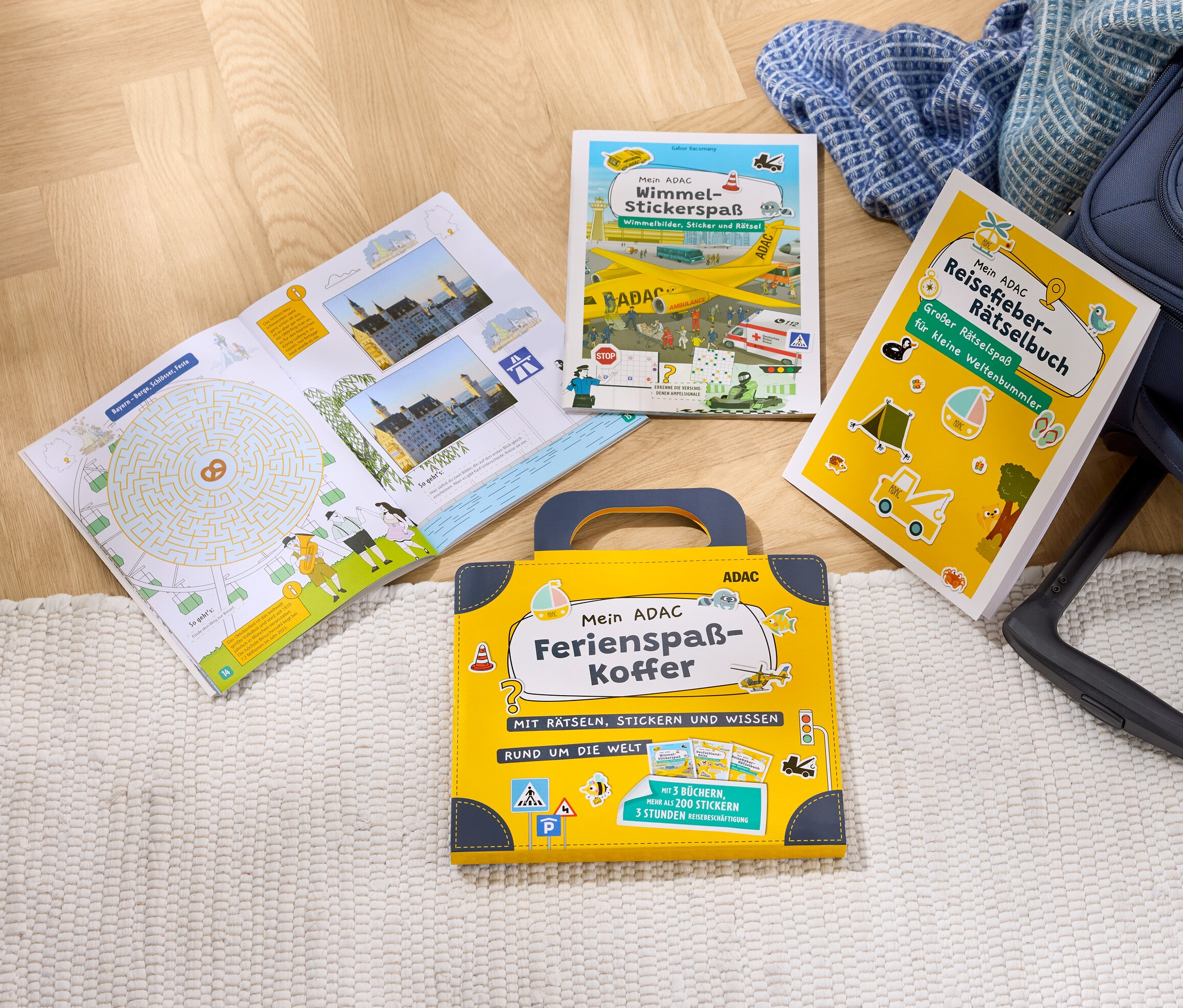 Das Bücher-Set »Mein ADAC Ferienspaß-Koffer« liegt auf dem Boden neben einem Koffer.