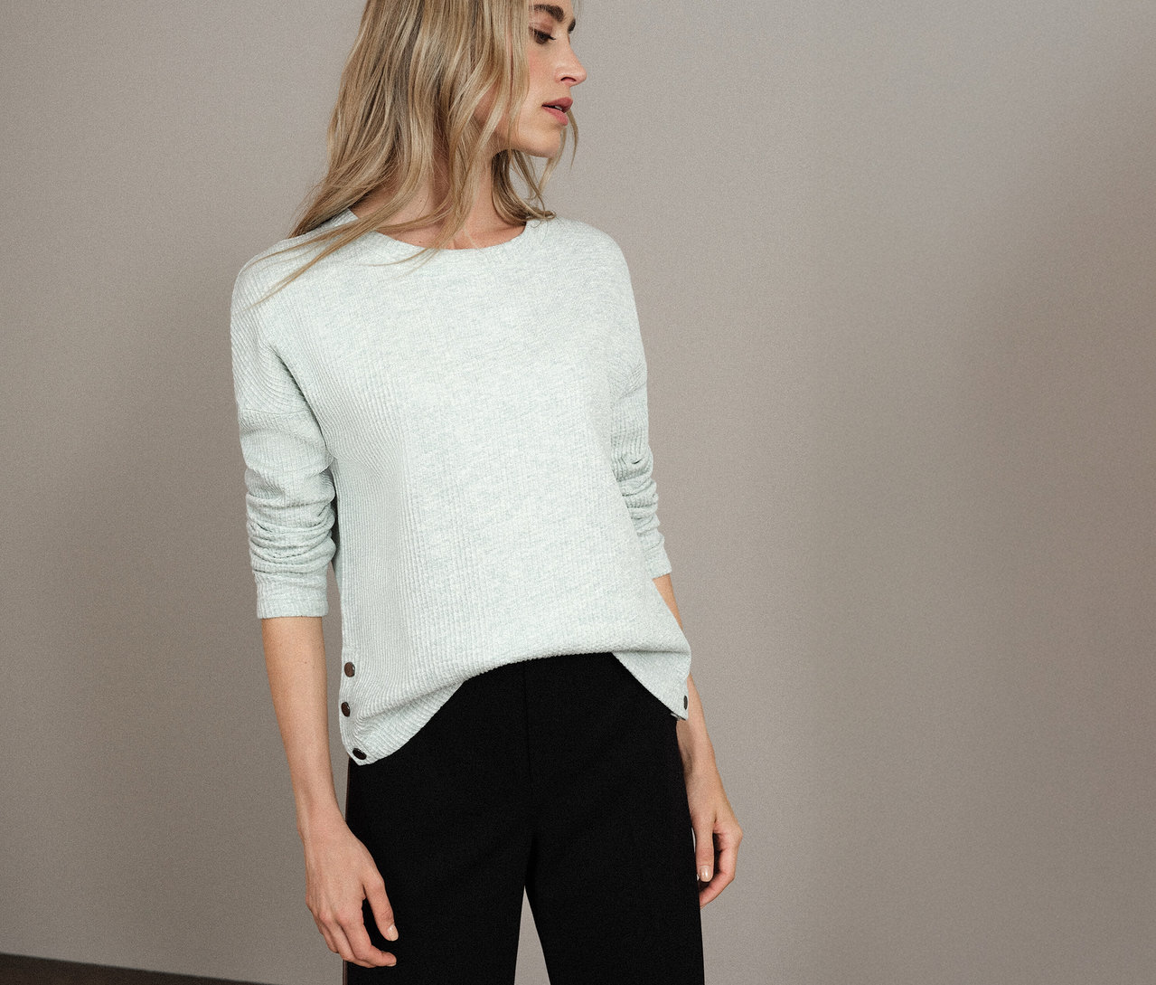 Frau trägt ein hellblaues Street One Shirt mit Struktur und eine schwarze Hose.